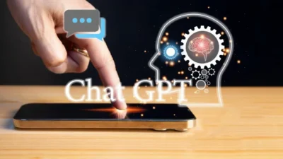 A sales professional engaging with ChatGPT on a laptop while drafting personalized emails.